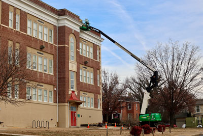 Worker on lift repairing R. S. Payne Elementary exterior