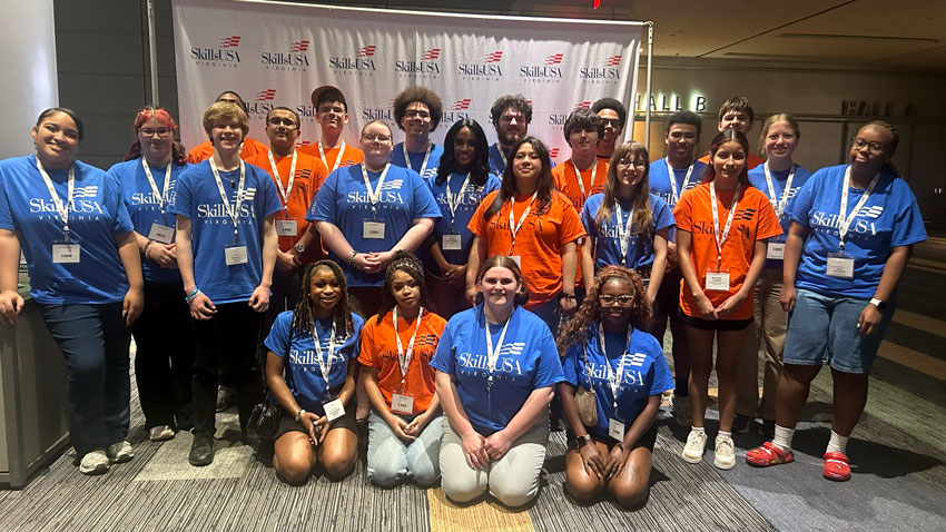 Large group of students wearing SkillsUSA t-shirts standing in front of conference backdrop