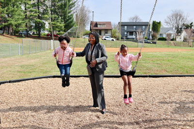 Superintendent pushing girls on swings