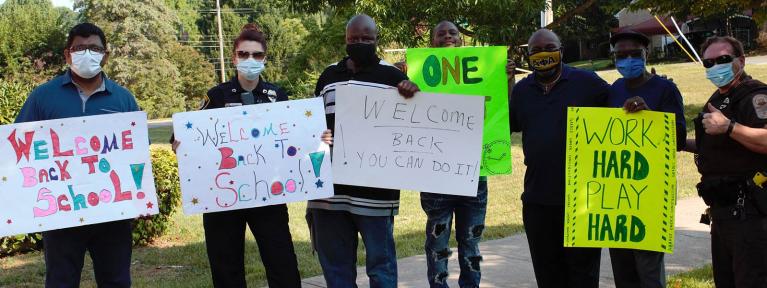 Volunteers holding back to school signs