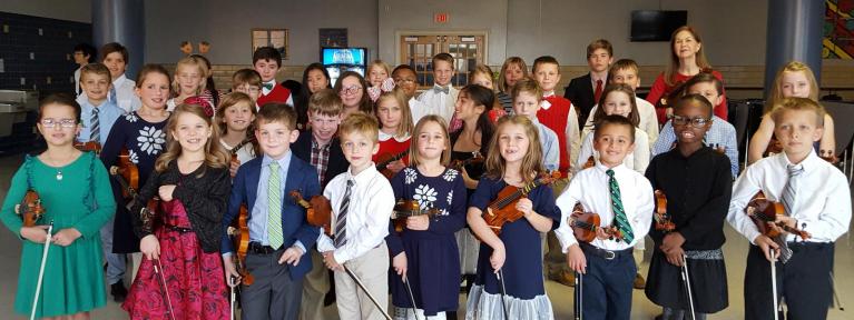Large group of strings students standing with violins