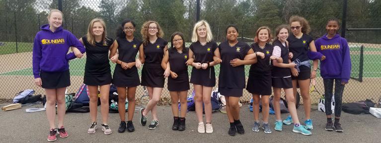 Girls tennis team posing together locking arms