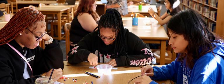 Three girls at table in library working on project