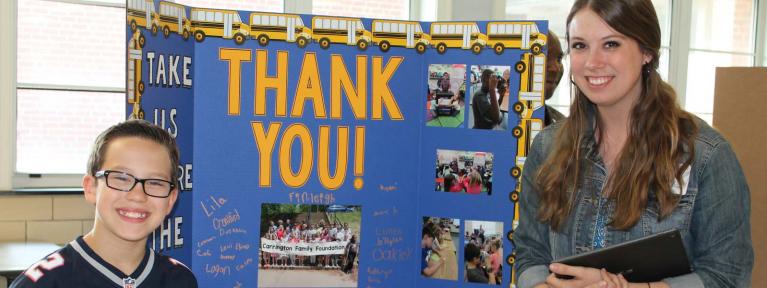 Teacher and student standing in front of display board that reads "Thank You"