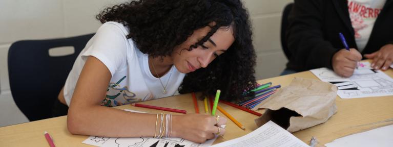 Student using colored pencils at table
