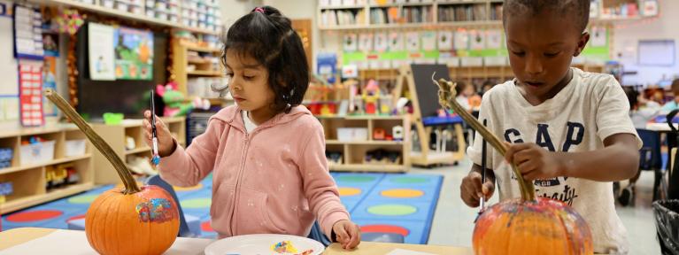 Two pre-k students painting pumpkins