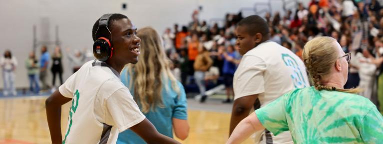 Two student participating in Medford League basketball game with assistance from staff