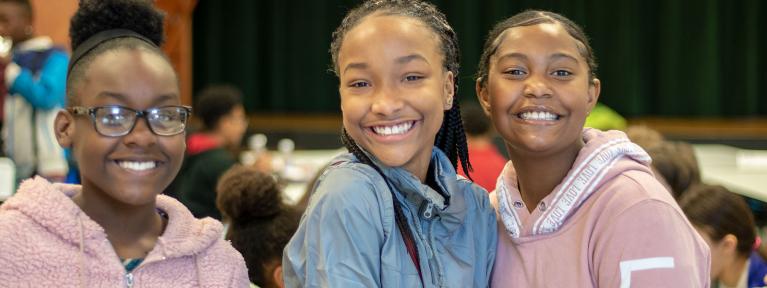 Three girls smiling in cafeteria