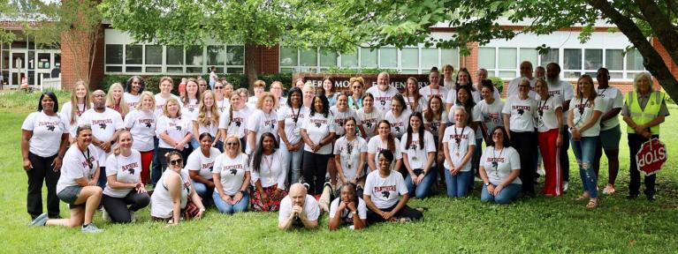 School staff in matching shirts standing in from of building