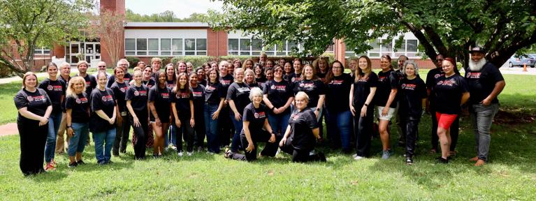 School staff in matching shirts standing in from of building