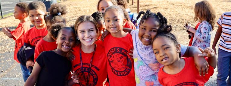 Smiling teacher and students on playground in matching R. S. Payne shirts