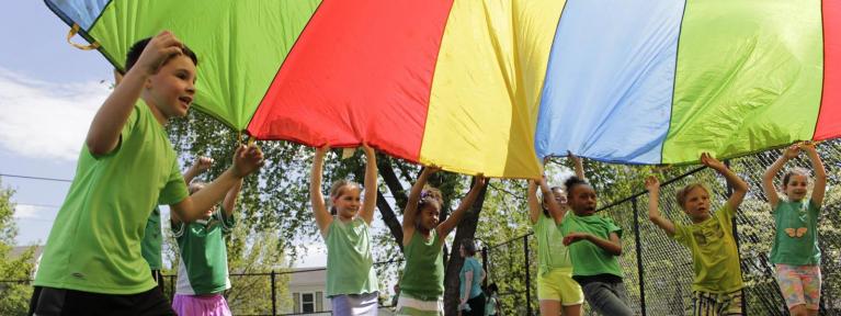 Students playing with rainbow color parachute