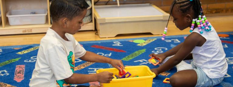 Two students on rug playing with shapes